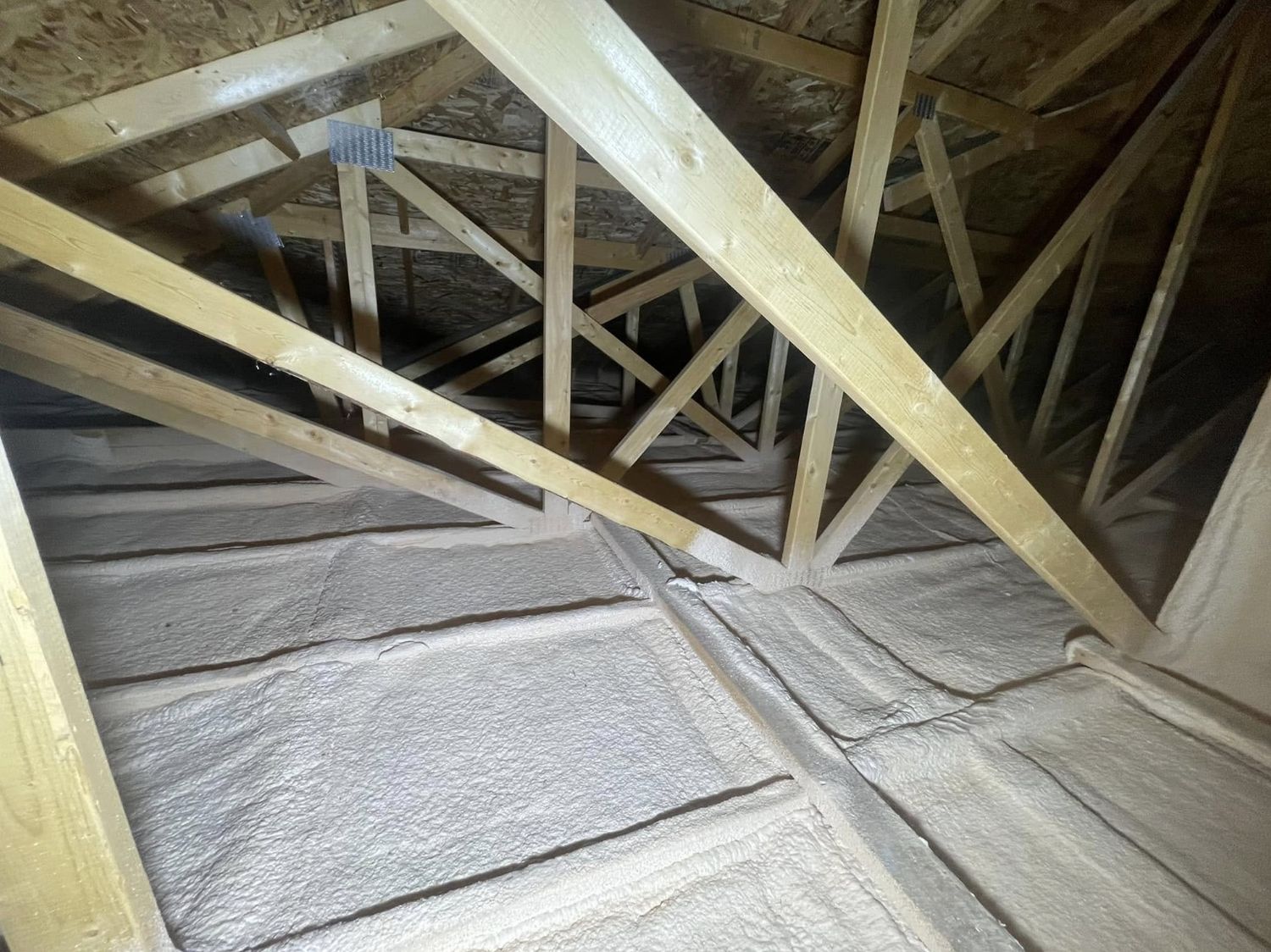 Attic floor spray foamed under roof trusses