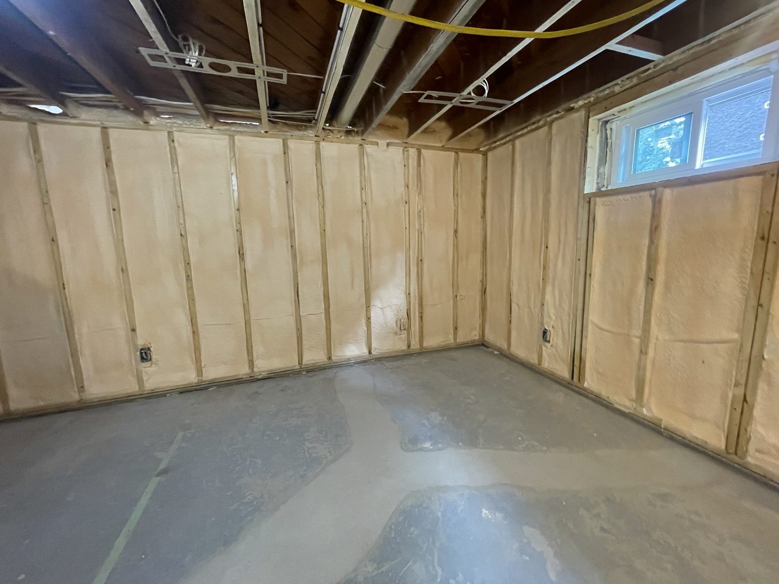 Basement room with every stud bay and the rim joist spray foamed, bare concrete floor