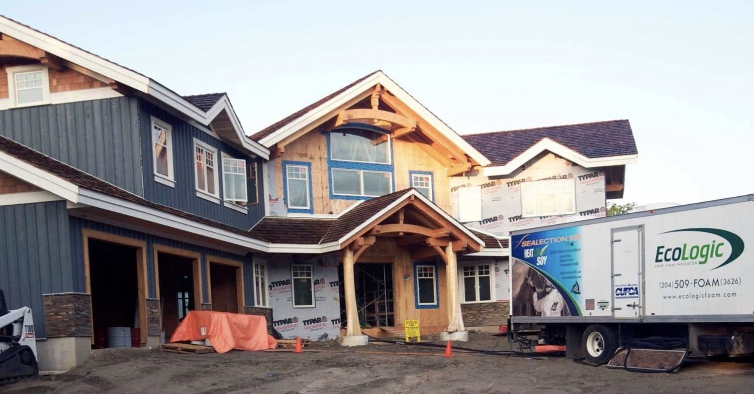 EcoLogic spray foam truck parked in front of a new house under construction wrapped in house wrap