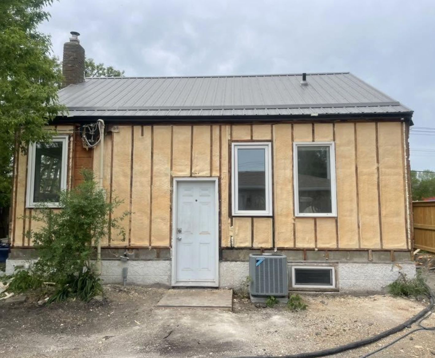 Exterior wall cavity spray foamed on a house with a metal roof visible behind it