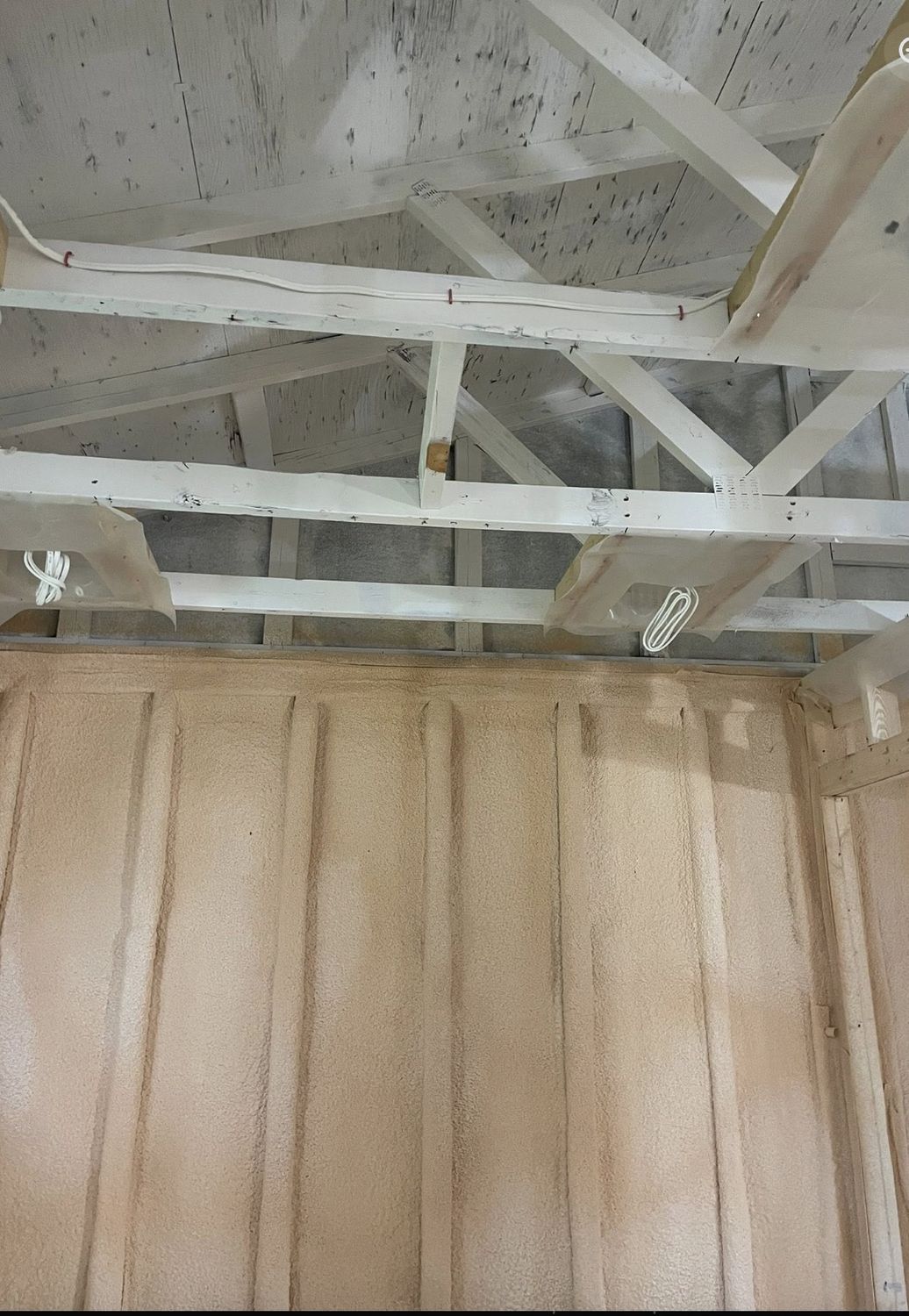 Garage wall spray foamed between exposed painted roof trusses